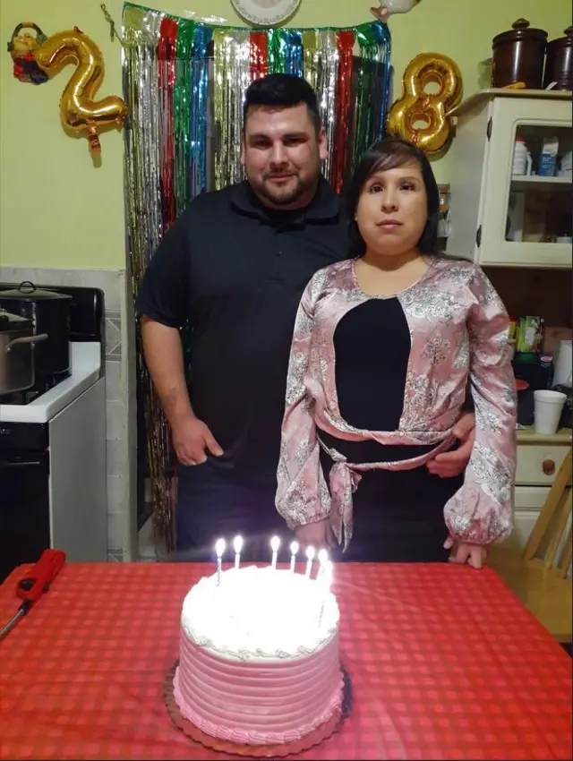 Jessica López y Christopher frente a un pastel con velitas.