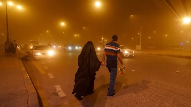 Muškarac i žena se drže za ruke u narandžastoj noći od peska