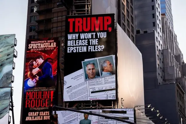 Una valla que dice: “Trump, why won’t you release the Eptein files?” y se ven fotos de documentos y dos fotos del rostro de Epstein. Al lado hay un cartel del musical Moulin Rouge!