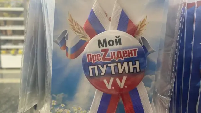 'পুতিন আমার প্রেসিডেন্ট' লেখা ব্যাজ বিক্রি হচ্ছে যেখানে প্রেসিডেন্ট শব্দটির বানানে S এর জায়গায় Z লেখা হয়েছে।