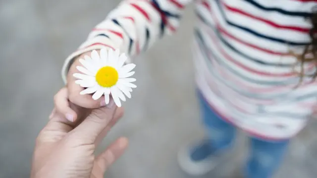 Niña sosteniendo una flor.