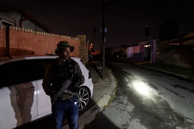 Un hombre armado junto a un auto