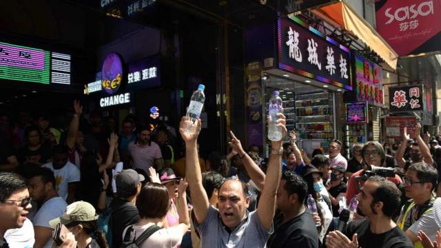 少数族群市民周日的游行期间，在重庆大厦大门向参加游行途经的人士派发瓶装水。