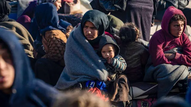 Una mujer kurda siria sostiene a un niño en Tabqa después de huir del norte de Alepo (4 de diciembre de 2024).