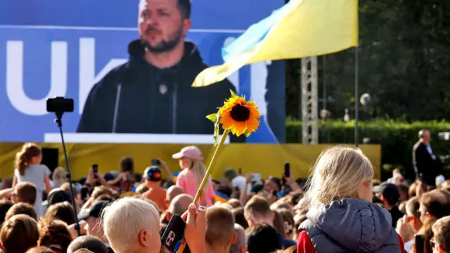 Abaturage barimo kureba ubwo Perezida wa Ukraine Volodymyr Zelensky yagezaga ijambo ku mbaga mu gace ka Lukiskiu Square mu murwa mukuru Vilnius wa Lithuania, ku itariki ya 11 Nyakanga (7) mu 2023, mu nama ya OTAN 