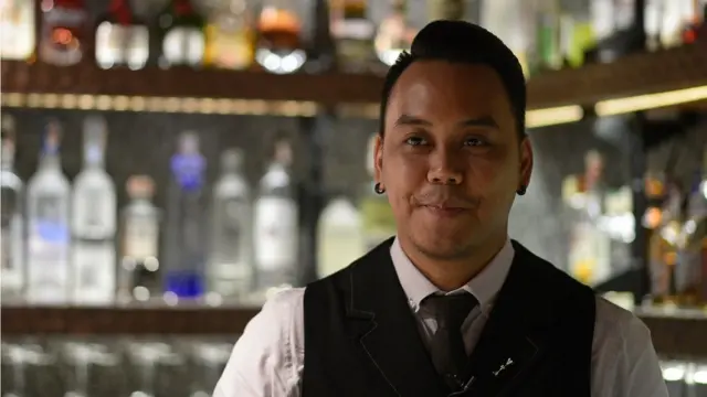 บุณธเนศยืนหน้าบาร์ยิ้ม