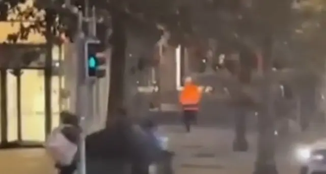 Тўқ сариқ курткадаги ҳужумчи милтиқ билан одамларни қувлаётгани видеода акс этган.