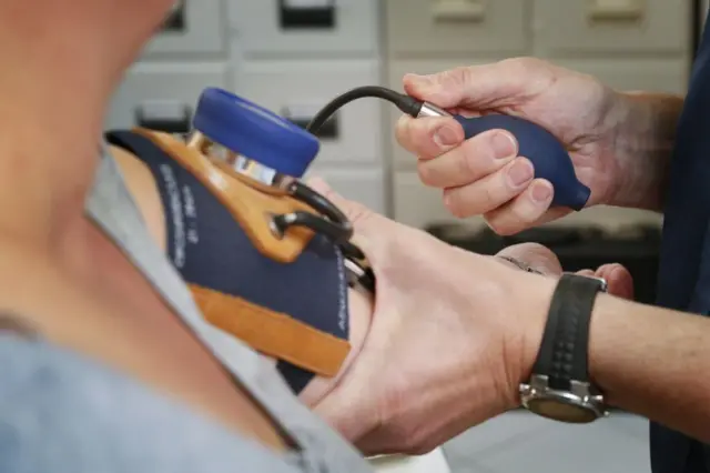 Un enfermero le toma la presión arterial a una paciente.