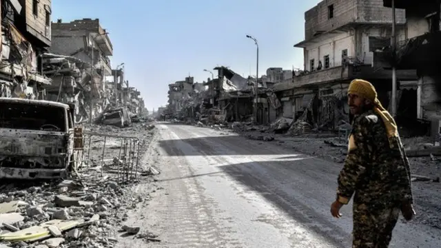 Kurdish fighter of di Syrian Democratic Forces dey walk for street for Raqa, Syria