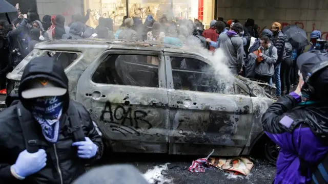 Manifestantes junto a un auto quemado en Seattle.