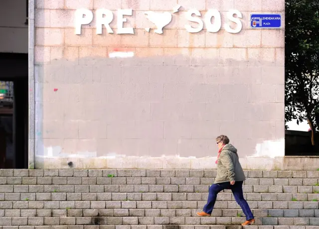 Mujer camina en Rentería, en la Comunidad Autónoma del País Vasco, España, el 8 de abril, ante una pared que reivindica el acercamiento de los presos de ETA a las cárceles del País Vasco.