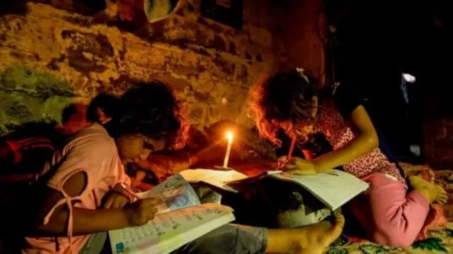 મીણબતીના અજવાળા હેઠળ ભણતા બાળકો
