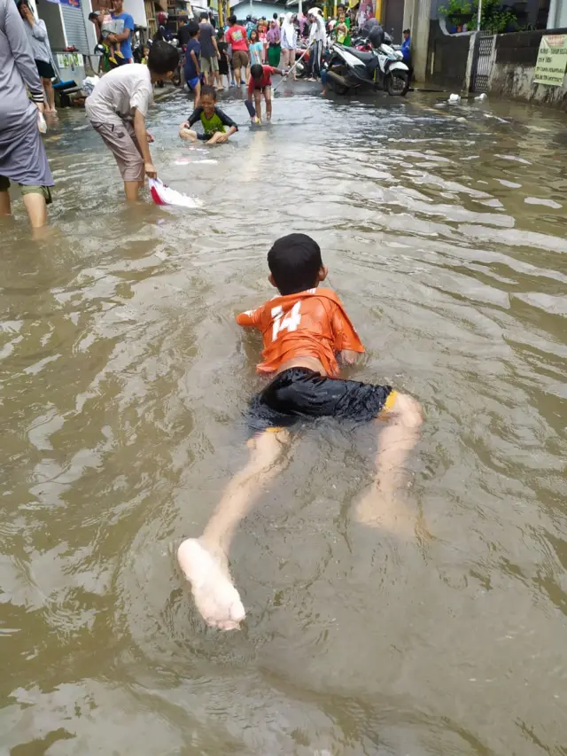 Anak-anak terlihat asik berenang saat hujan mengenangi Jakarta.