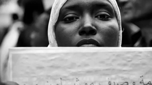 فتاة سمراء تحمل لافتة ضد العنصرية