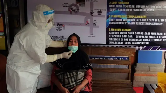 Petugas kesehatan mengambil sampel tes cepat antigen dari seorang penumpang bus di Terminal Tipe A Mengwi, Badung, Bali, Selasa (04/05)