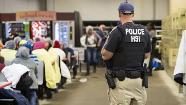 Un agente migratorio vigilando a un grupo de inmigrantes
