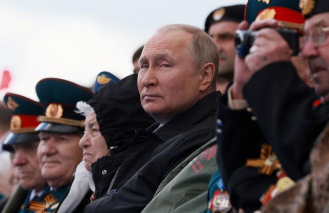 Vladimir Putin con otras personas viendo un desfile militar.