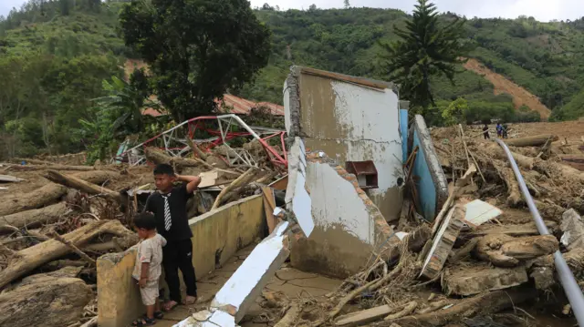 Dua orang anak melihat puing-puing rumahnya yang rusak pasca bencana di Desa Mendale, Kecamatan Kebayakan, Aceh Tengah, Aceh, Jumat (12/12/2025).