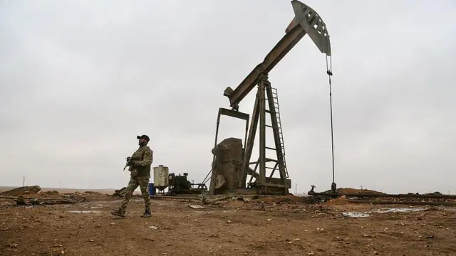 Petrol çıkarılan bir alanda silahlı bir erkek devriye geziyor.