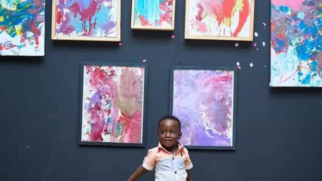 Un enfant en bas âge devant des peintures abstraites