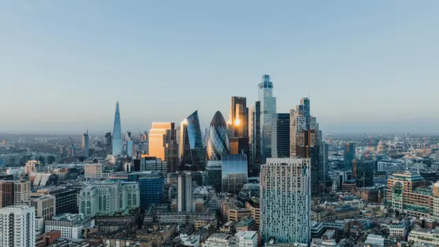 Tall glass skyscrapers in the City of London in a panoramic view of its skyline at sunset.