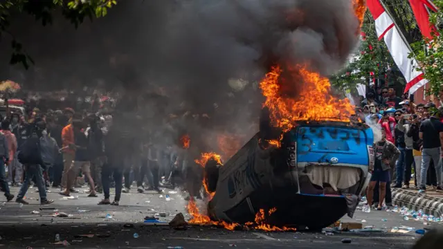Sebuah mobil polisi terbakar di jalan.