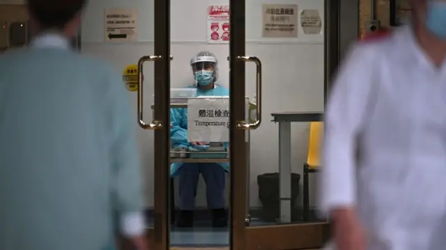 Hong Kong'daki Prenses Margaret Hastanesi'ndeki bir sağlık görevlisi hastaneye gelenlerin sıcaklıklarını ölçmek için bekliyor