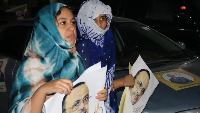 Des femmes, des affiches de leur candidat en main