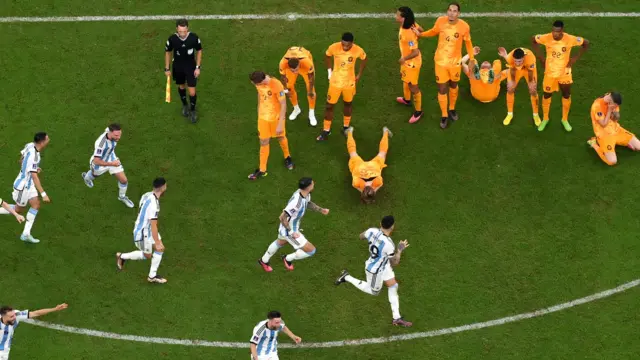 Uma foto aérea dos jogadores da Argentina comemorando diantebetsport comjogadores holandeses desanimados, alguns deitados no campo, depoisbetsport comvencer a disputabetsport compênaltis