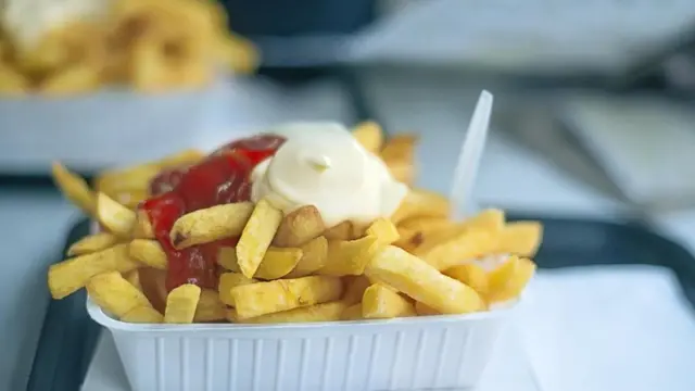 Un plato de papas fritas con ketchup y mayonesa