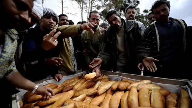 Rais wa Misri wakipewa mikate katika kambi ya wakimbizi viungani mwa mji wa Misrata, Libya Machi 31,2011 wakisubiri kuokolewa kutoka kwenye taifa hilo