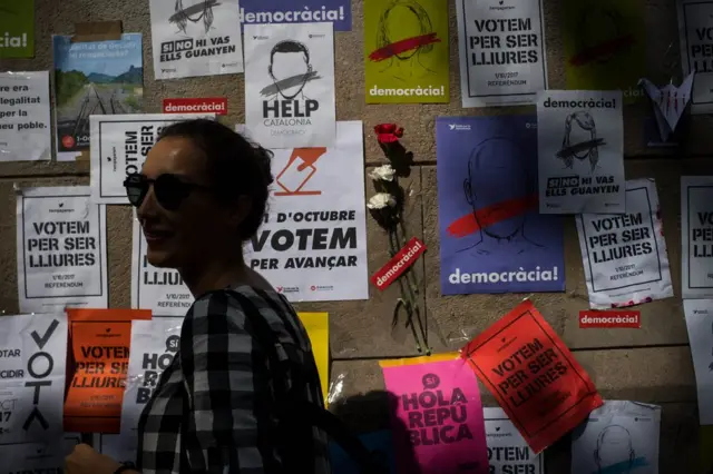 Mujer frente a carteles que llaman a votar en el referéndum para la independencia de Cataluña del 1 de octubre.