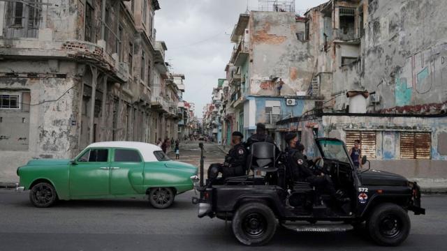 Una unidad de las fuerzas especiales se cruza con un auto clásico en La Habana