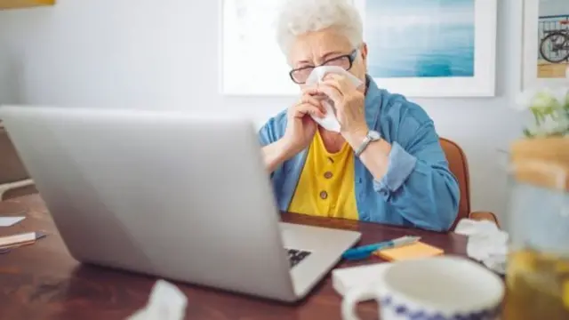 Mujer de la tercera edad frente a una computadora portátil.