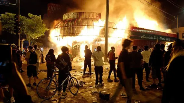 Pessoas observam um incêndio de um comércio