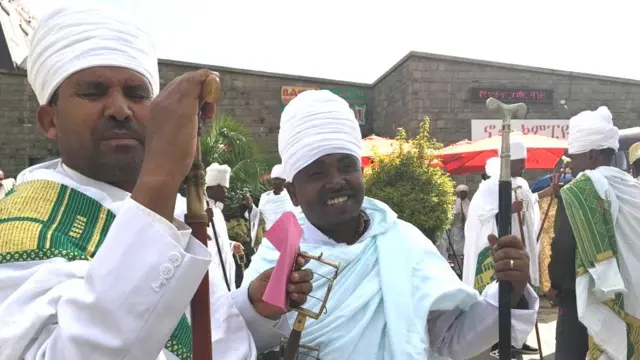 ከፀሐይ የተጠለሉ የኃይማኖት አባቶች ለአፍታ ለፎቶ ፈገግ ብለው