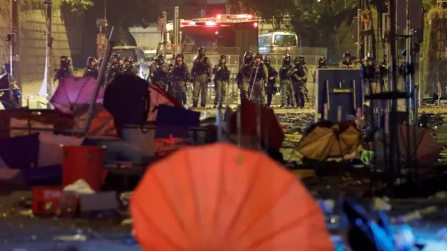 Police officers stand guard in front of a street scattered with umbrellas outside Hong Kong Polytechnic University (PolyU) in Hong Kong, China, November 19, 2019