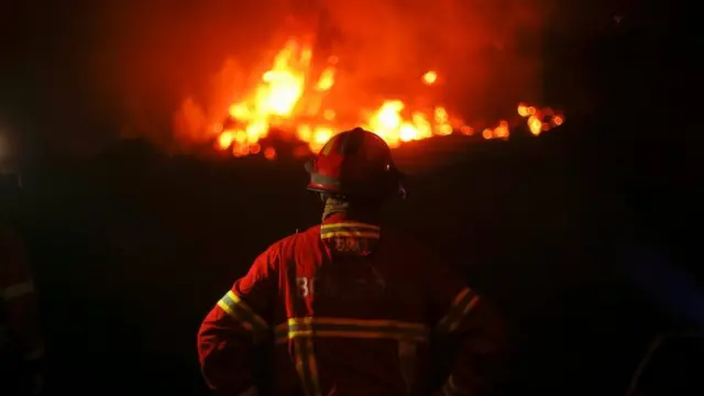 رجل أطفاء يقف أمام حرائق الغابات في البرتغال