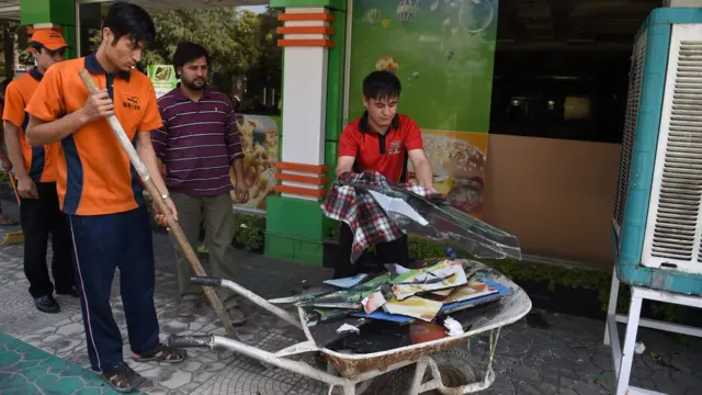 Afghan waiters clear broken glass in front a hotel near the site of an attack on a charity in central at the Shar-e-Naw in Kabul on 6 September