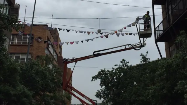 Un collaborateur de l'auteure de l'exposition met la corde à linge, qui s'étire sur 1,2 kilomètre.