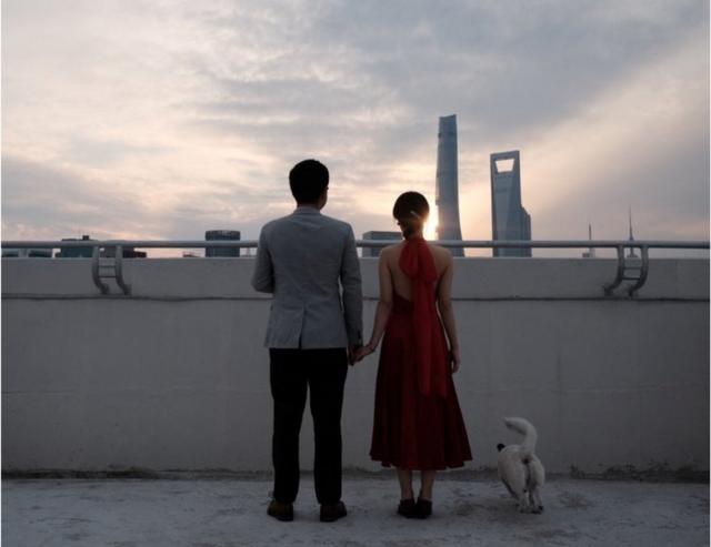 上海爆发新冠疫情并宣布封锁后，一对新婚夫妇在住宅区一栋建筑物的屋顶上合影留念