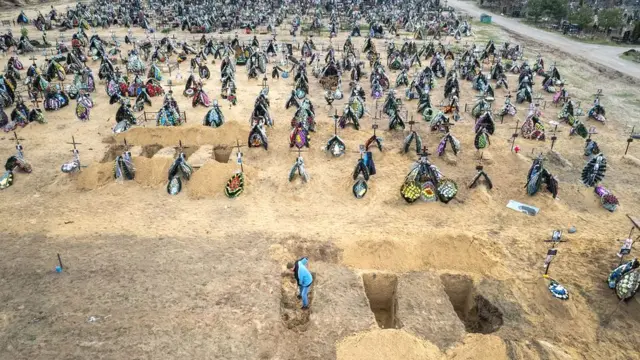 A gravedigger prepares the ground for a funeral at a cemetery in Irpin, Ukraine. The first several rows contain people killed during the Russian occupation of the area.