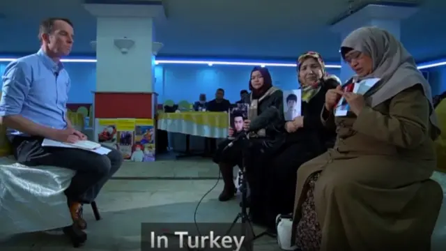 Стамбулда ондогон ата-энелер чоң залда кезекке туруп, Синцзянда калган балдарынын сүрөтүн кармап, өздөрүнүн башынан өткөн оор окуяларды айтып берип атышат.