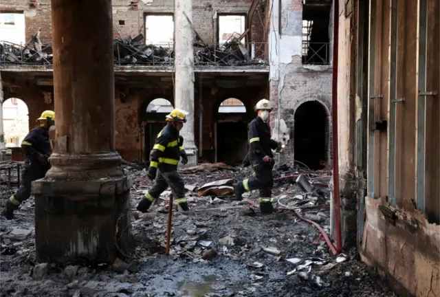 Firemen walk through the burnt out remains of Jagger Library at the University of Cape Town.