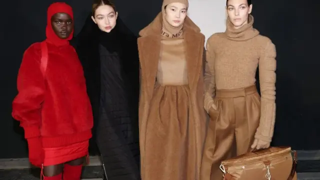Four models posing for a picture. Akon Changkou is on the far left and is wearing a bright red outfit with a hood.