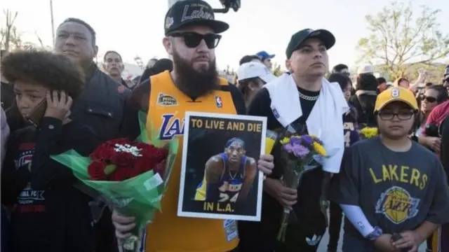 LA Lakers fans gada near di site of di crash to pay dia respect