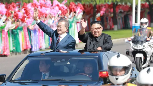 This picture taken on September 18, 2018 and released by Korean Central News Agency (KCNA) via KNS shows North Korean leader Kim Jong Un (R) and South Korean President Moon Jae-in (L) waving to Pyongyang citizens from an open-topped vehicle as they drive through Pyongyang.