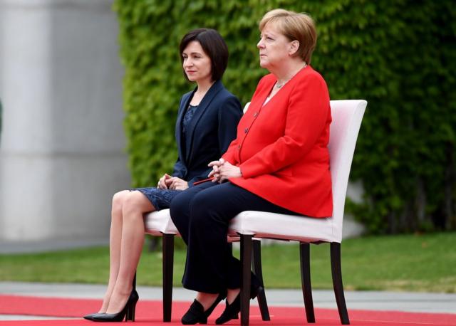 La canciller de Alemania, Ángela Merkel (der.) y la primera ministra de Moldavia, Maia Sandu, sentadas escuchando los himnos nacionales durante una recepción en Berlín, 16 de julio de 2019