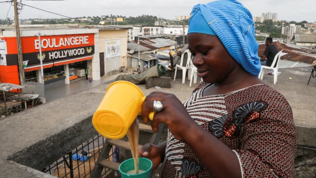 Mwanamke anachanganya kinywaji katika eneo la Adjame, Abidjan, Ivory Coast - Jumapili Machi 20