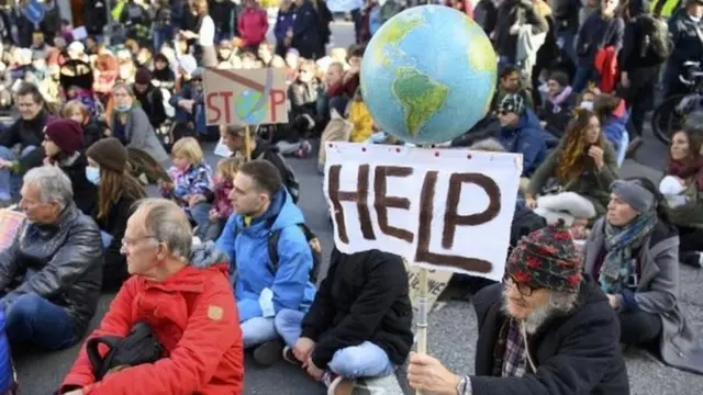 A protester holds a globe and a slogan that reads "Help" during a rally in Lausanne, Switzerland. Photo: November 2021